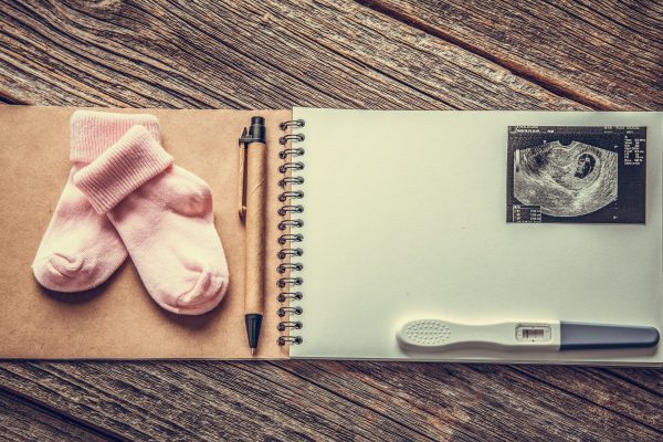 An album with baby socks, a pen, pregnancy test and scan